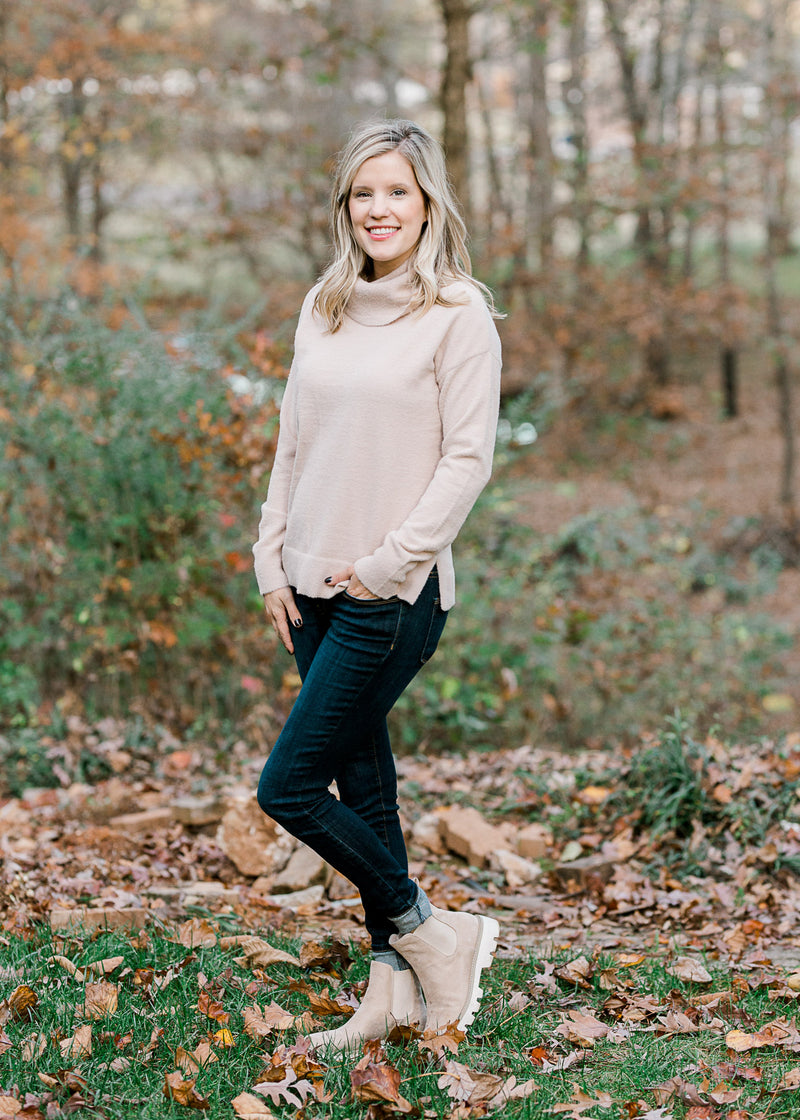 Blonde model wearing a taupe sweater with jeans and booties. 