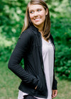 Close up of Brunette model wearing front zip athleisure jacket.