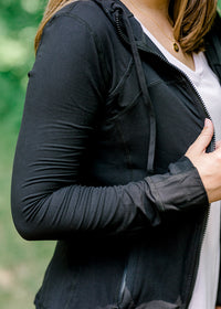 Zip and tie detail of Brunette model wearing front zip athleisure jacket.