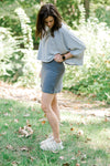Brunette model wearing a gray tennis skirt.