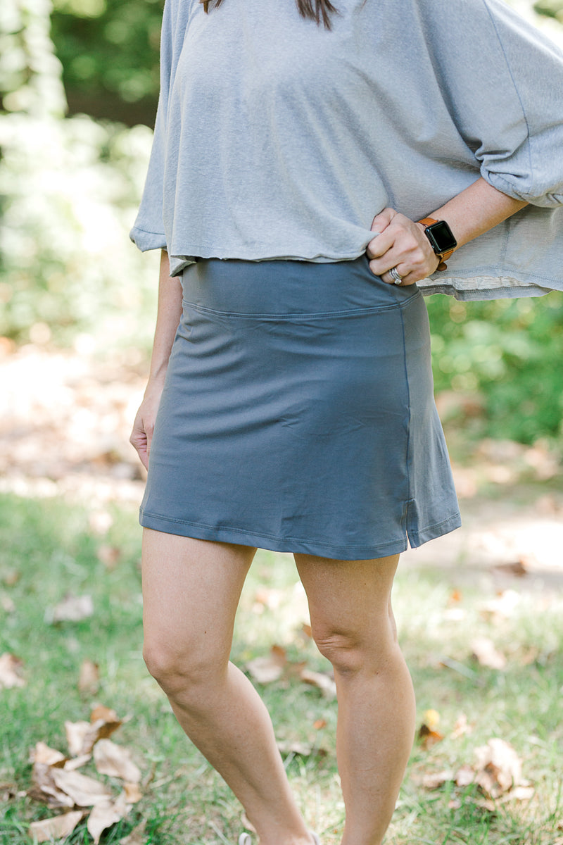 Detail of brunette model wearing a gray tennis skirt.