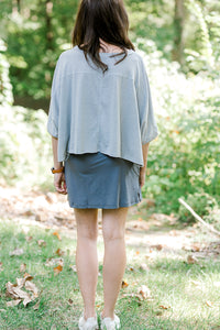 BAck view o fBrunette model wearing a gray tennis skirt.