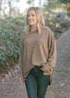 Blonde model wearing heathered light brown sweater. 