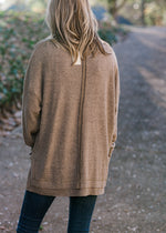 Back view of Blonde model wearing heathered light brown sweater.