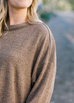 Close up view of Blonde model wearing heathered light brown sweater.