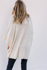 Back view of Blonde model wearing a cream cardigan with batwing sleeves. 