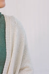 Close up view of Blonde model wearing a cream cardigan with batwing sleeves. 