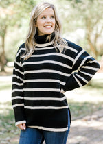 Blonde model wearing black and white striped sweater with a turtleneck.