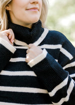 Close up of turtleneck on Blonde model wearing black and white striped sweater.
