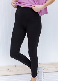 Waist detail of Model wearing full length black leggings.