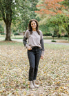 Brunette model wearing ash and charcoal two toned top with black jeans and booties.