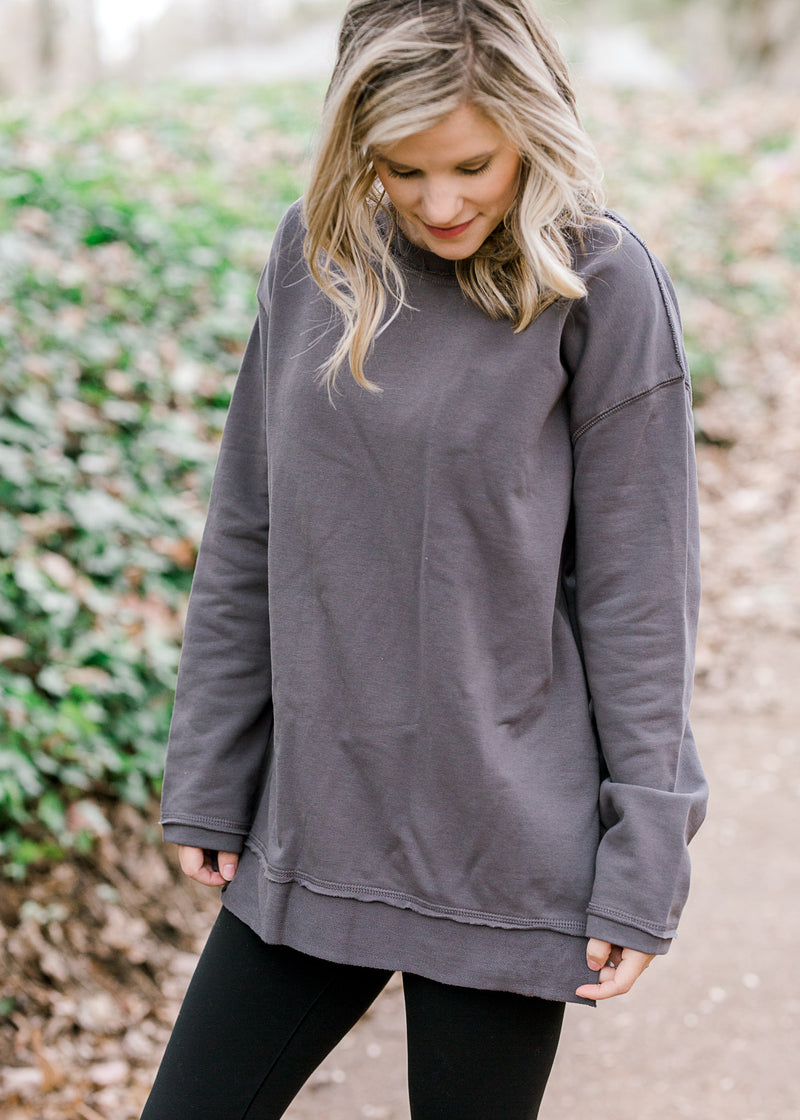Blonde model wearing charcoal top with layered hem.