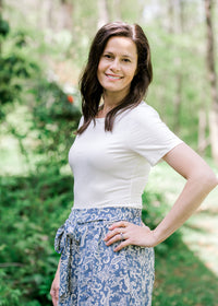 Brunette model wearing short sleeve ivory body suit.