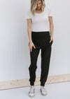 Blonde model wearing a white bodysuit with black joggers and sneakers.
