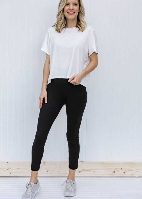 Blonde model wearing black yoga pants with side pocket and tennis shoes.